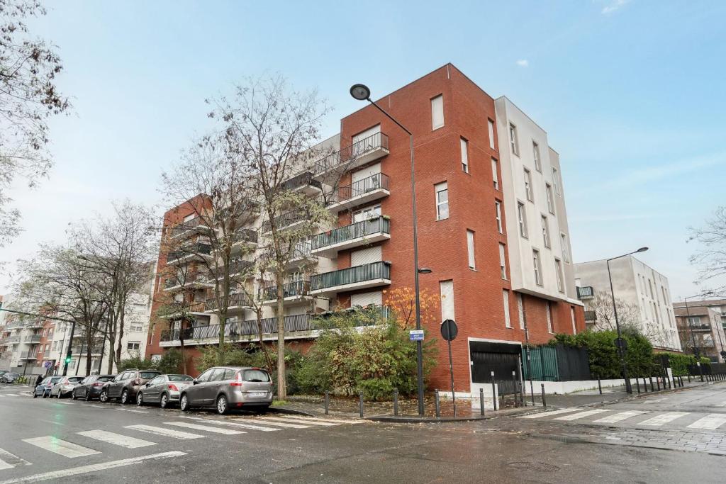 a red brick building with cars parked in front of it at Magnifique Appart Stade de France gare Terasse Paris 6 pers in Saint-Denis