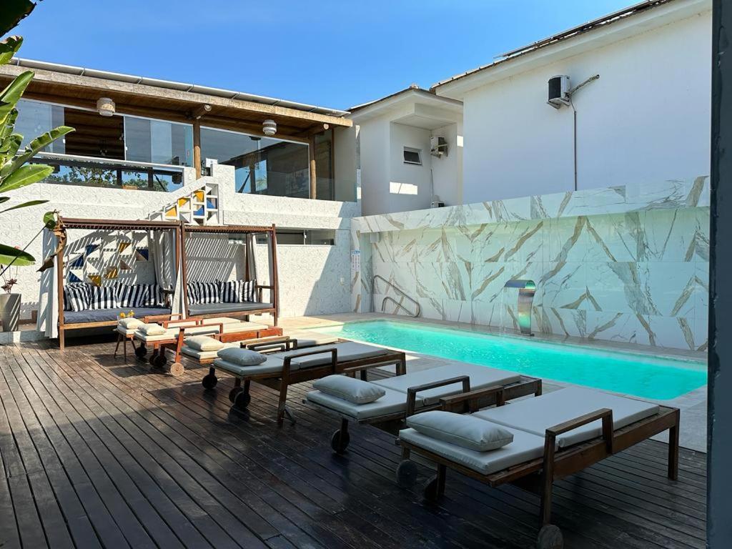 uma piscina com cadeiras e bancos ao lado de um edifício em Santorini Beach Hotel em Arraial d'Ajuda