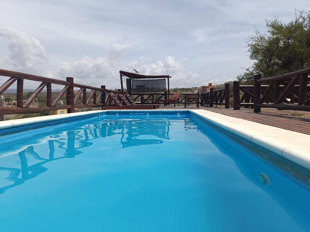a blue swimming pool with a wooden fence at Cabañas La Colina in Estancia Vieja