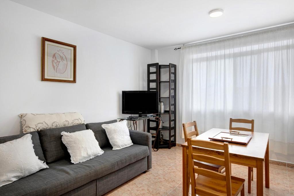ein Wohnzimmer mit einem Sofa, einem Tisch und einem TV in der Unterkunft Apartamento Rebeca in Tazacorte