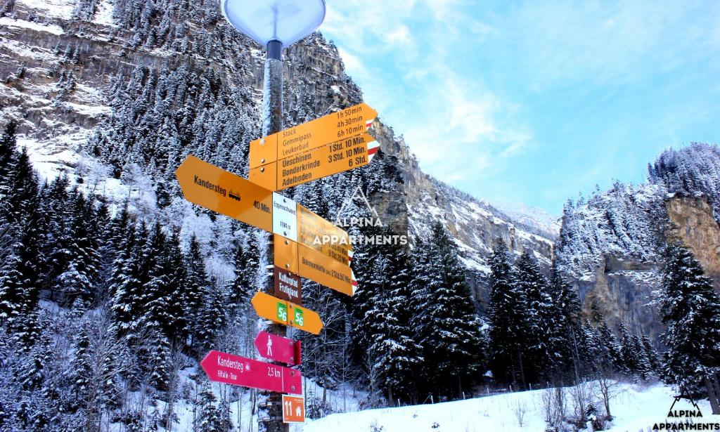 Une bande de panneaux sur un poteau dans la neige dans l'établissement Alpina Appartment 2, à Kandersteg