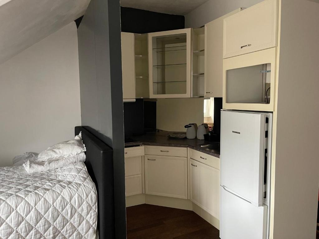 uma pequena cozinha com armários brancos e um frigorífico branco em B&B Santorini em Maasbree