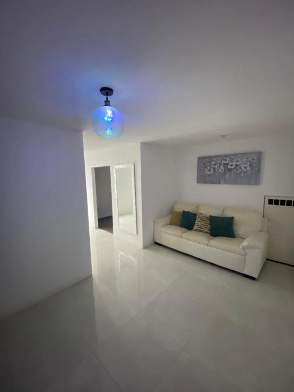 a white living room with a couch and a blue light at Casa ideal para familias estadías largas y cortas in Manta