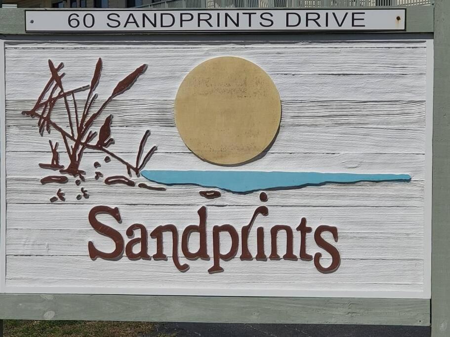 um sinal que diz dólares de areia numa parede de madeira em “Sandprints” em Destin