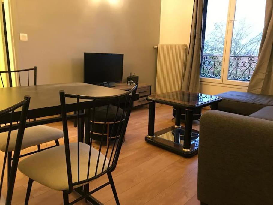 uma sala de estar com uma mesa e cadeiras e um sofá em PARIS- Défense/Puteaux Appartement Cartault em Puteaux