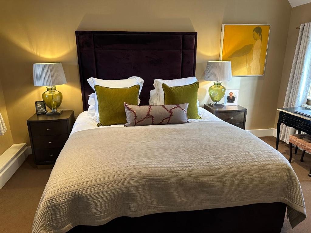 a bedroom with a large bed with green pillows at The Red Lion in Blewbury