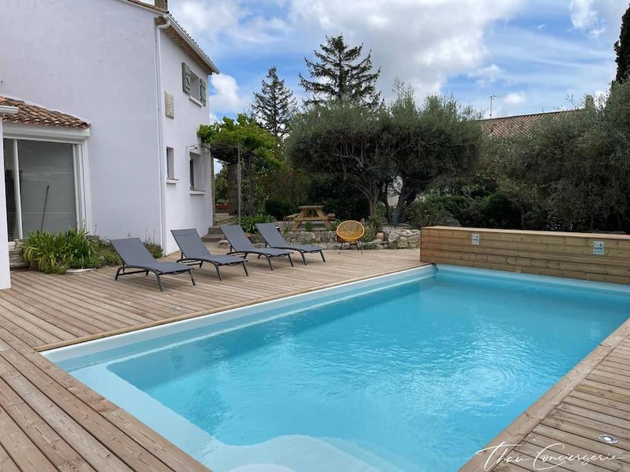 a swimming pool with lounge chairs next to a house at Poussan, Villa des Oliviers, superbe villa classé in Poussan