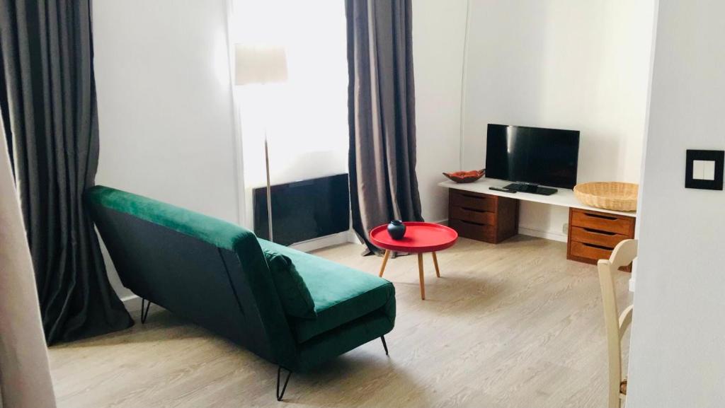- un salon avec un canapé vert et un bureau dans l'établissement Le Saint Jean, à La Rochelle