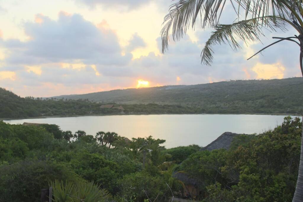 una vista de un lago con la puesta de sol a lo lejos en Charming Eco Cabin - Inhambane, en Ligogo