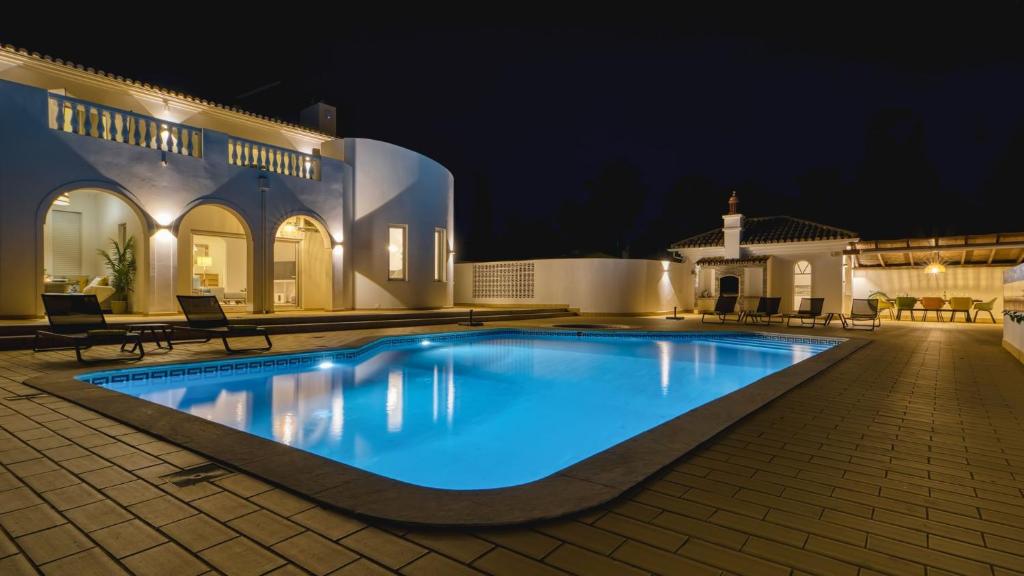 a swimming pool in front of a house at night at Villa Beleza in Portimão