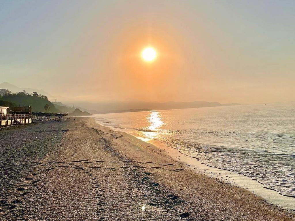 una playa con puesta de sol sobre el agua en Mirando al Mar tu Hogar de Playa - Ideal para familias - Parking Incluido, en Torrox Costa