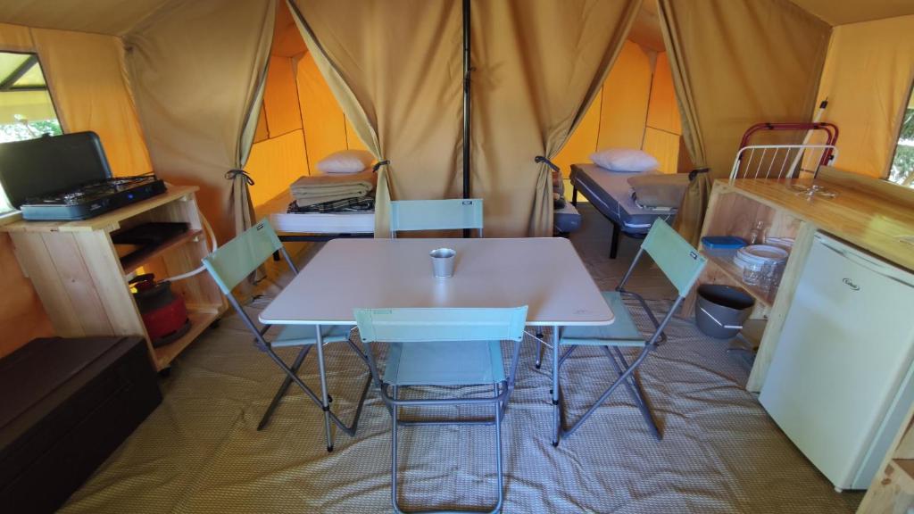 une tente avec une table blanche et des chaises. dans l'établissement Camping ONLYCAMP LES PINS, à Nançay