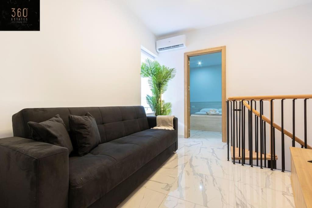 a living room with a brown couch and a staircase at A lovely duplex maisonette just of Spinola w/WIFI by 360 Estates in St. Julianʼs