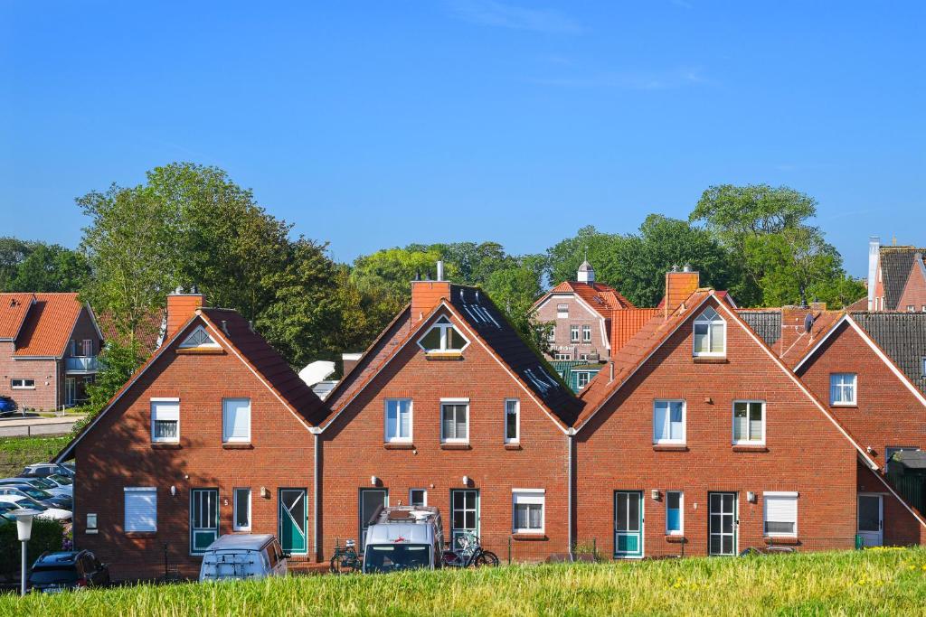a large red brick building with a group of houses at Ferienwohnung Baltrum Inselhaus am Deich in Neuharlingersiel