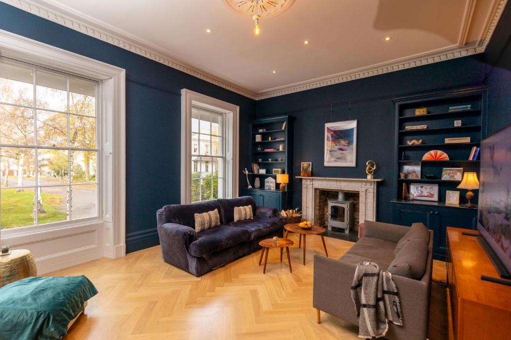 a living room with blue walls and a couch and a fireplace at Pittville House in Cheltenham