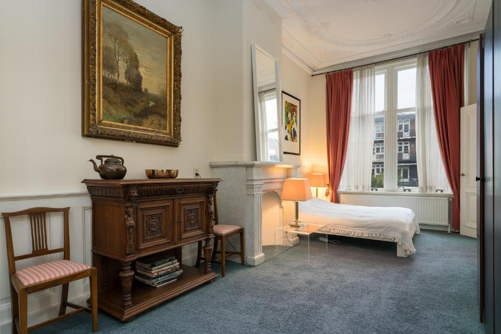 um quarto com uma cama, uma lareira e uma cadeira em Vondelparkmuseum Inn em Amsterdã