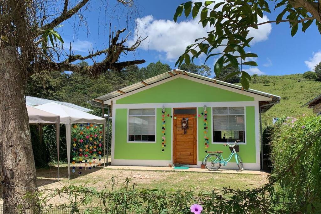 ein kleines grünes Haus mit einem Fahrrad davor in der Unterkunft Cabañitas Shollet in Oxapampa