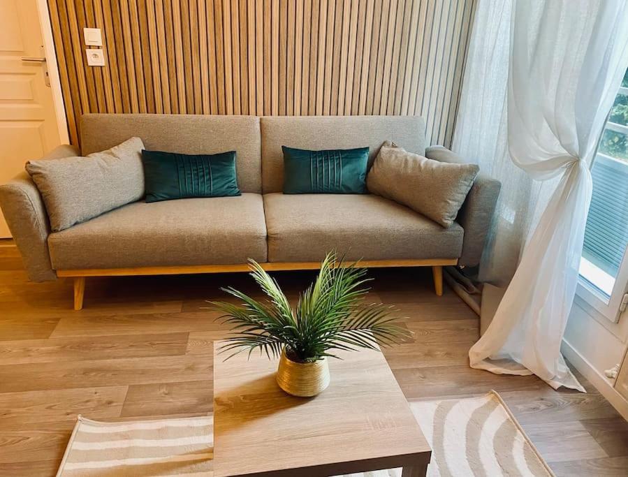 un sofá en una sala de estar con mesa en Charmant T2 moderne /proximité CDG / Confort, en Villepinte