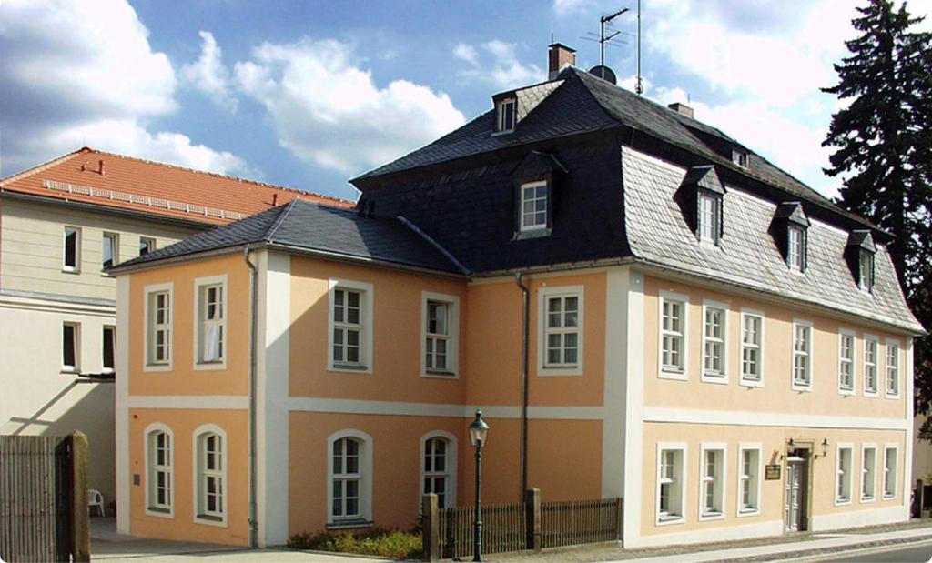 ein großes orangefarbenes und weißes Gebäude mit schwarzem Dach in der Unterkunft Komenský Gäste- und Tagungshaus in Herrnhut