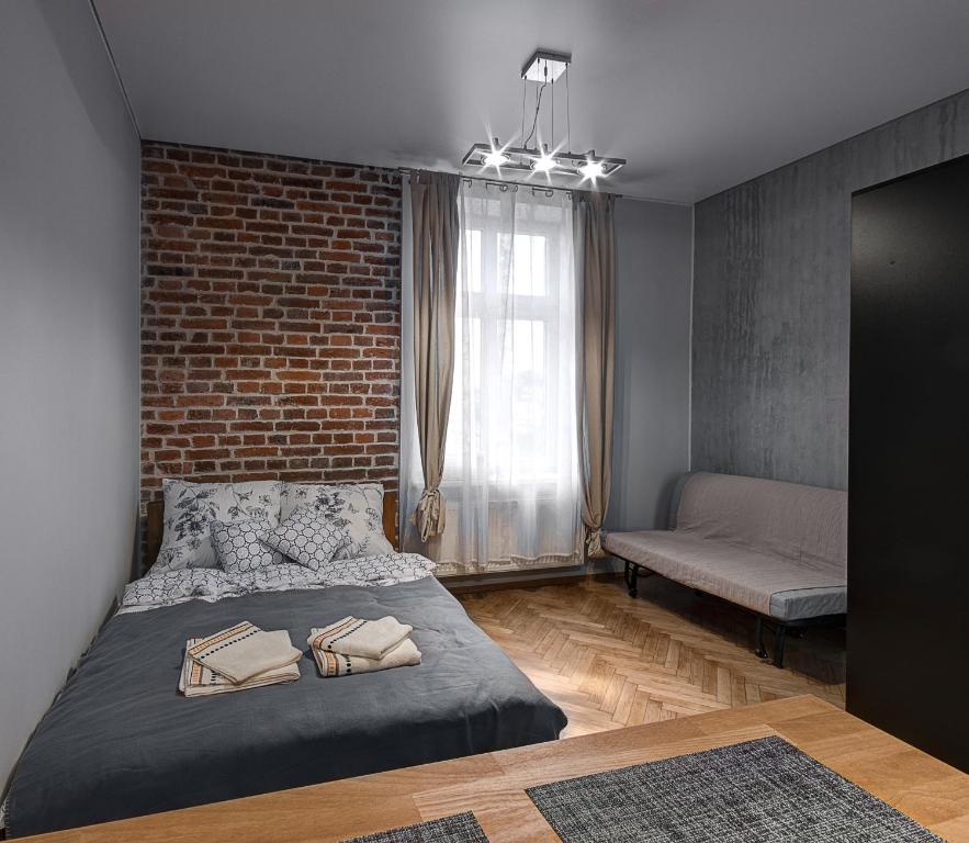 1 dormitorio con cama y pared de ladrillo en Lost In Krakow Apartments, en Cracovia