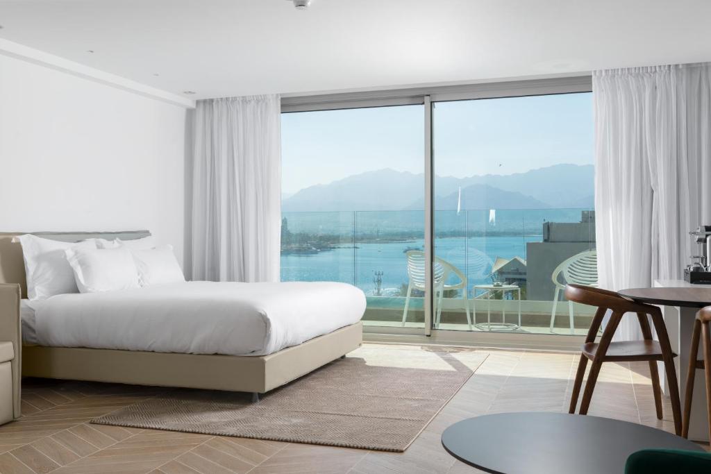 a bedroom with a bed and a large window at AKOYA HOTEL in Eilat