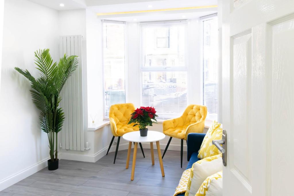 a room with two yellow chairs and a table with flowers at Open Mind Property - 6 Luxury Bedrooms with Free Parking in Portsmouth
