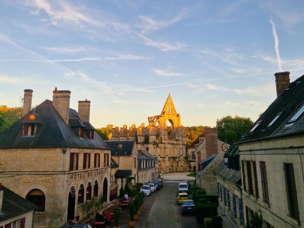 an old town with a castle in the background at HOTEL DE L'ABBAYE DE LONGPONT in Longpont