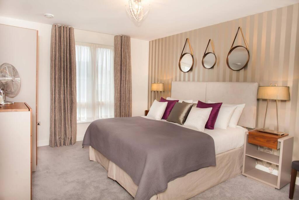 een slaapkamer met een groot bed met paarse kussens bij Stylish and central two bedroom & two bathroom apartment with free parking in Bath