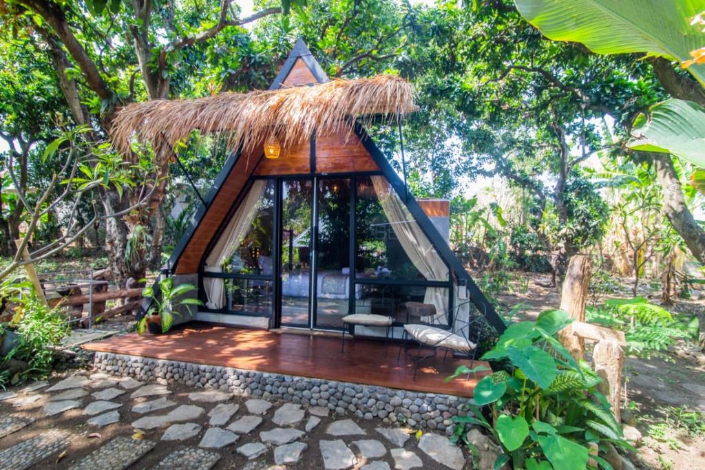 una pequeña casa en el bosque con techo de paja en Mangoforest Bali, en Panji