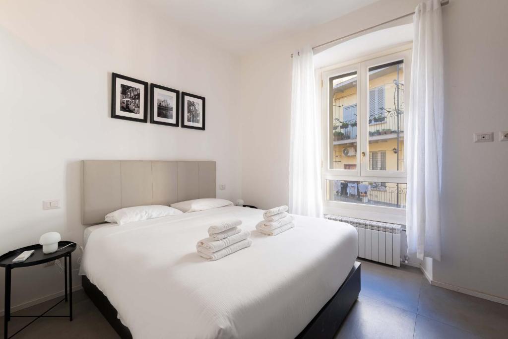 biała sypialnia z dużym łóżkiem i oknem w obiekcie Rivin Apartment w Mediolanie