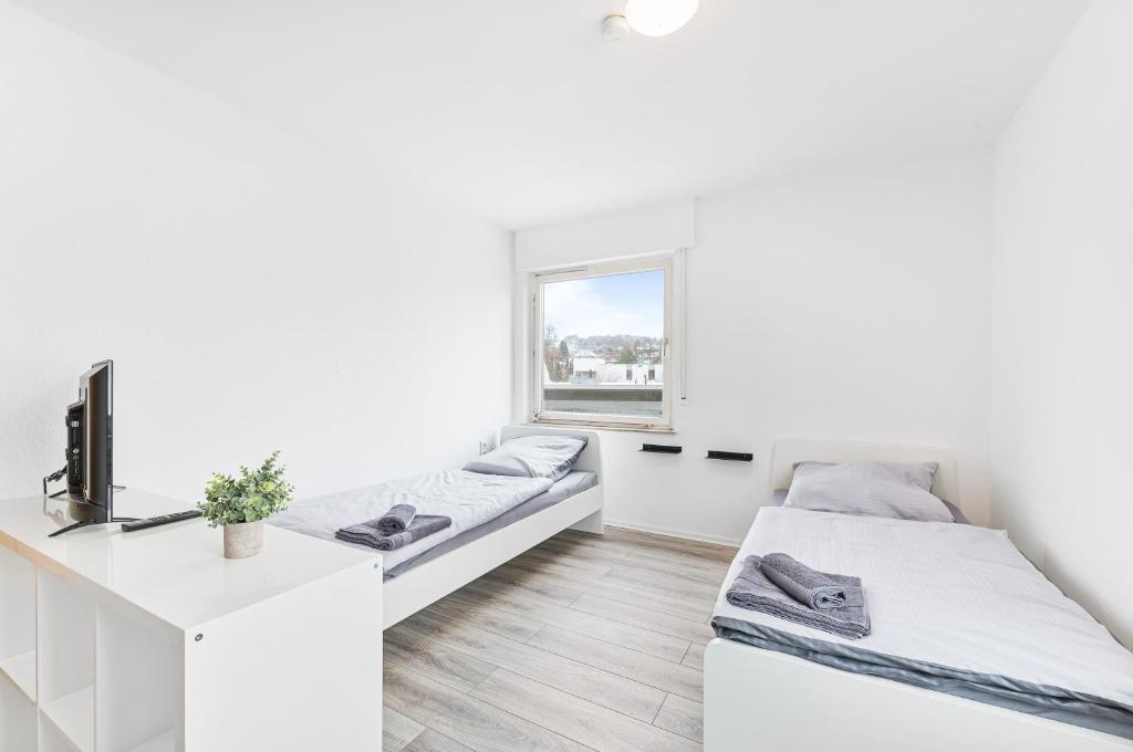 een witte kamer met 2 bedden en een bureau bij MONTEURWOHNUNG in Ebersbach EB02 RAUMSCHMIDE Apartments in Ebersbach an der Fils
