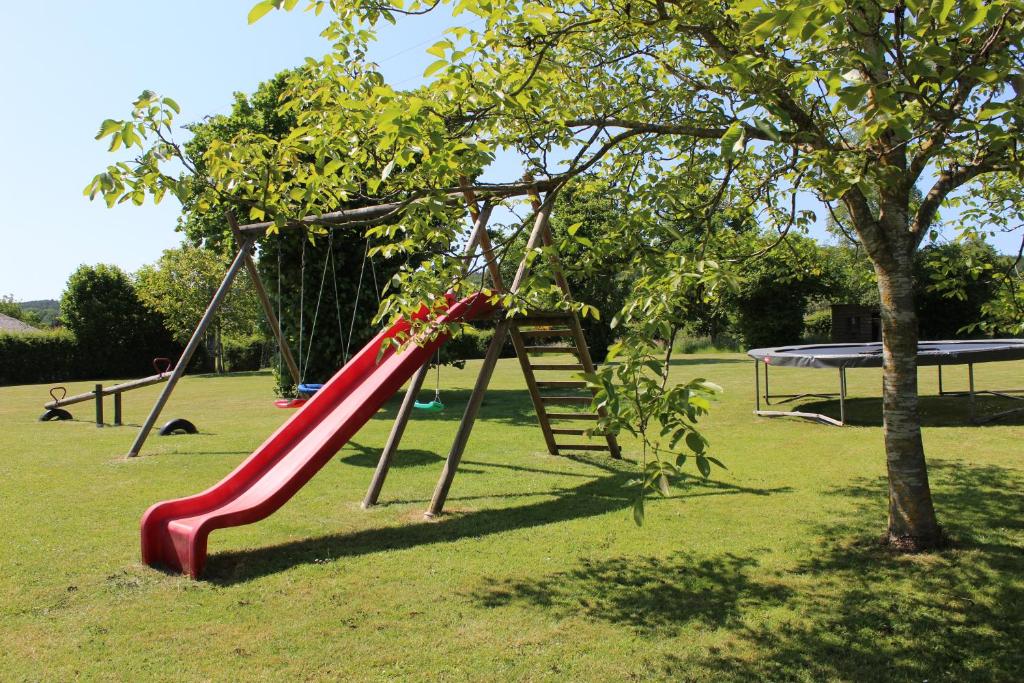 a red slide in a park with a tree at La Gendarmerie in Chevron