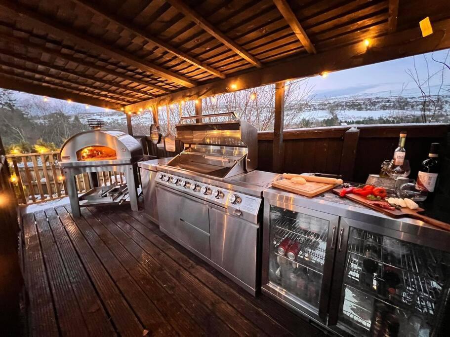 uma cozinha exterior com comodidades para churrascos num deque em 3 - Spectacular Views - Pizza Oven & BBQ em Pont Sticill