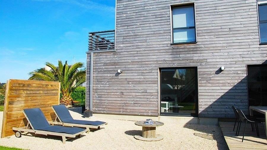 dwa krzesła i stół przed domem w obiekcie Villa en bois VUE MER avec jardin clos, WIFI, à 500m plage à l'Ile Grande en PLEUMEUR-BODOU REF-269 w mieście Pleumeur-Bodou