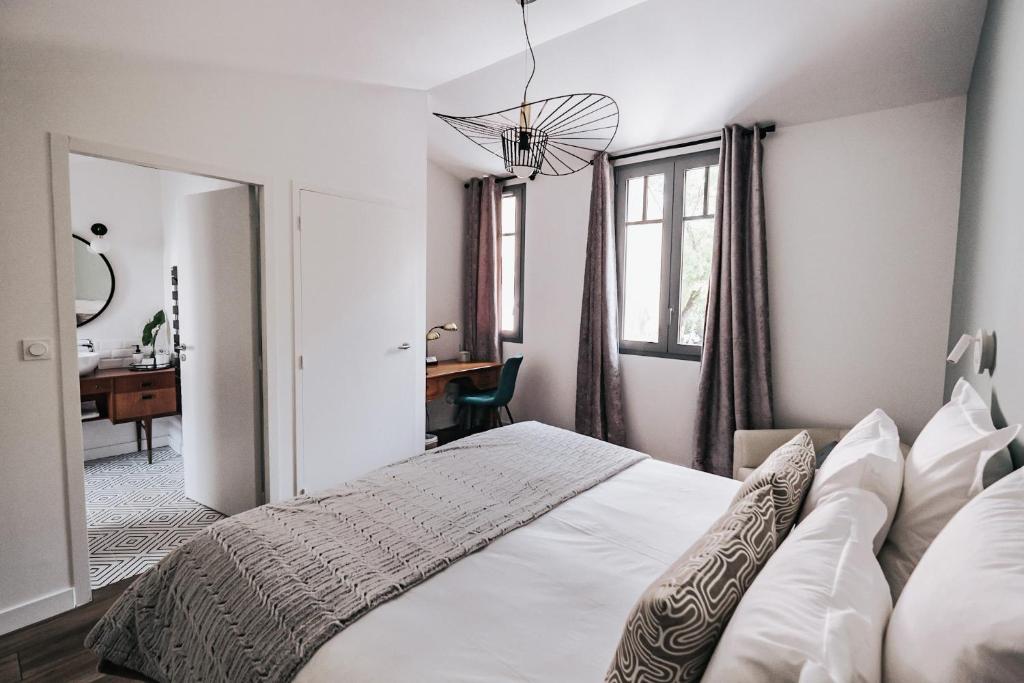 une chambre avec un lit blanc et un bureau dans l'établissement 64 Sur Le Mail, à La Rochelle