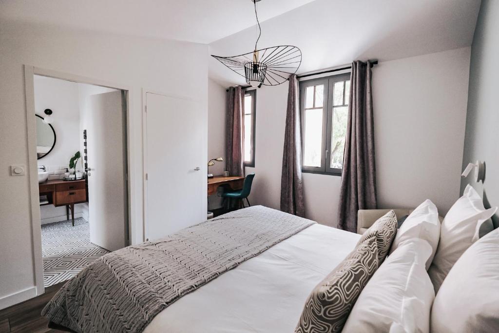 - une chambre avec un lit blanc et un bureau dans l'établissement 64 Sur Le Mail, à La Rochelle