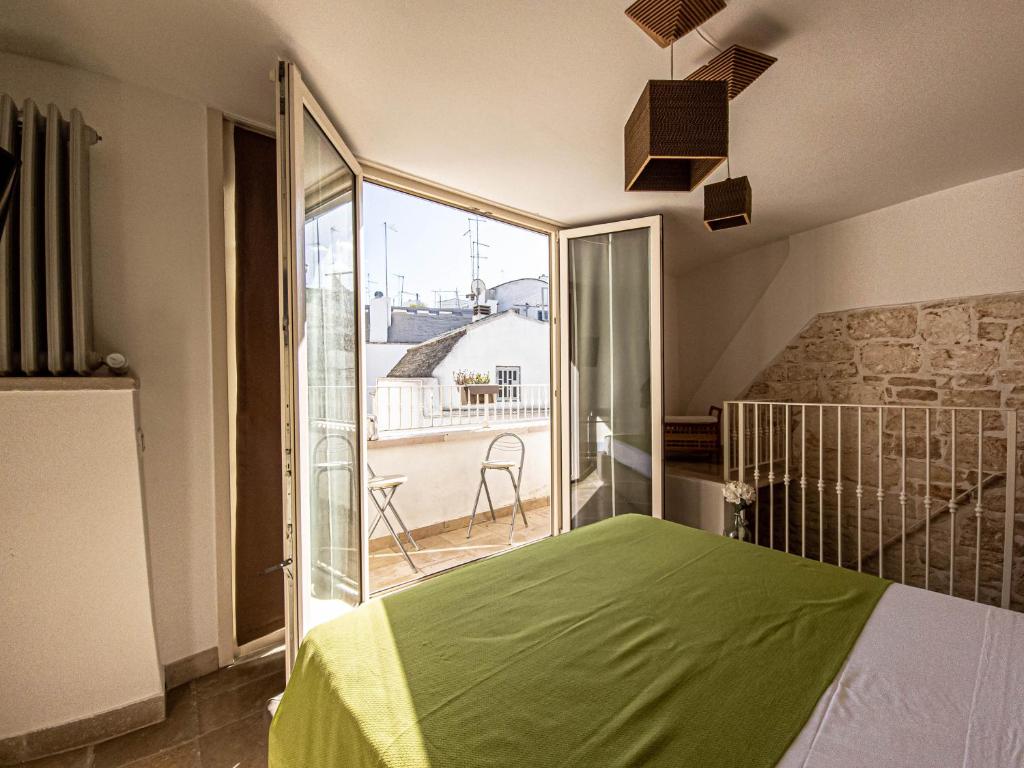 1 dormitorio con cama verde y balcón en Martine Dimore Storiche di Puglia, en Martina Franca