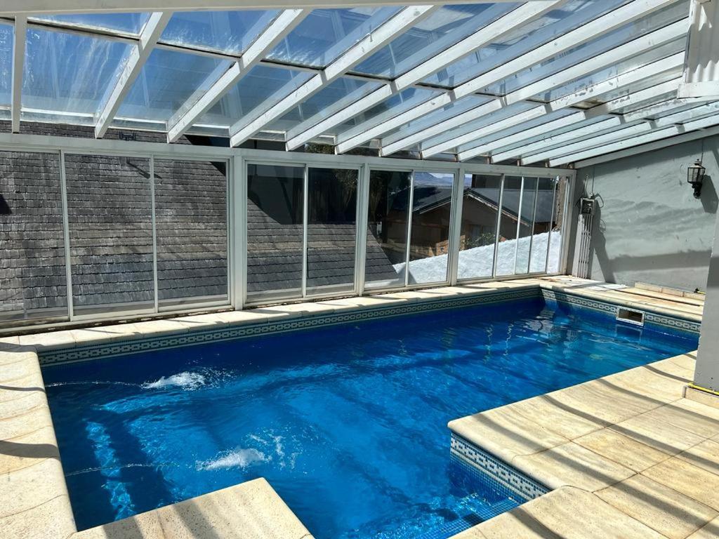 a swimming pool with a glass roof and a swimming poolvisor at Casa con pileta climatizada privada in San Carlos de Bariloche
