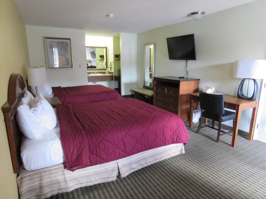 Habitación de hotel con cama, escritorio y TV. en Thunderbird Motel, en Elko