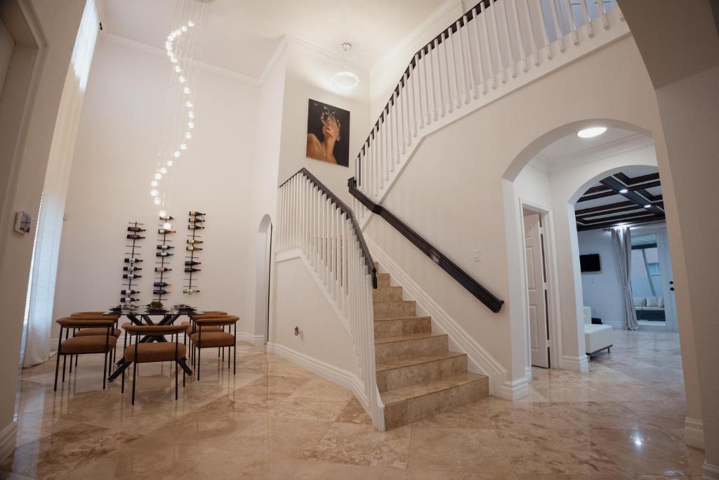 ein Esszimmer mit einer Treppe, einem Tisch und Stühlen in der Unterkunft Miami Getaway Heated Pool Villa with Mini Golf &amp; BBQ in Miami