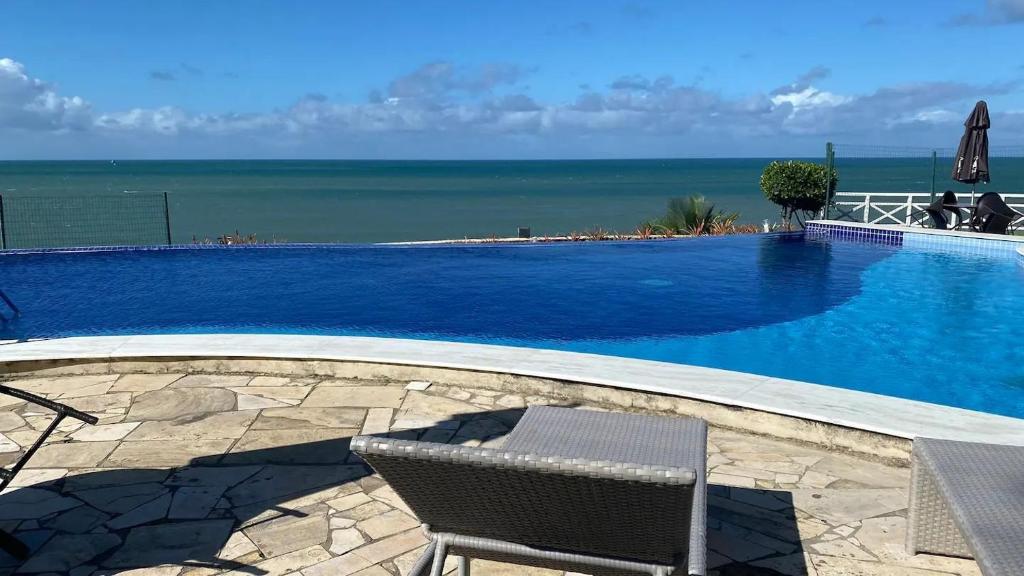 una piscina con 2 sillas y el océano en Porto Brasil Resort, en Parnamirim