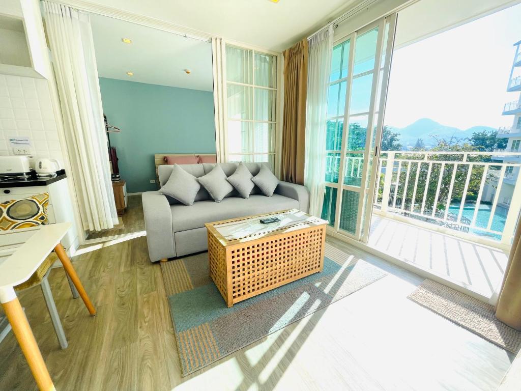 een woonkamer met een bank en een groot raam bij Summer Huahin 323,Near Beach&Cicada,Beautiful swimming pool in Hua Hin