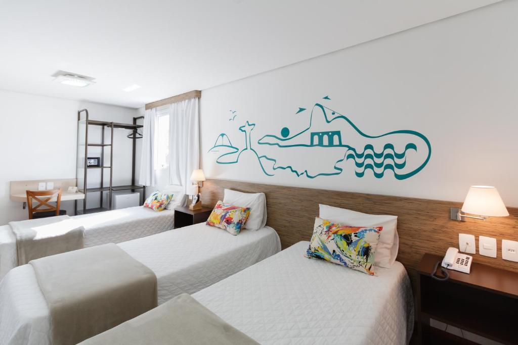 a hotel room with three beds and a mural on the wall at Garibaldi Business Hotel in Porto Alegre