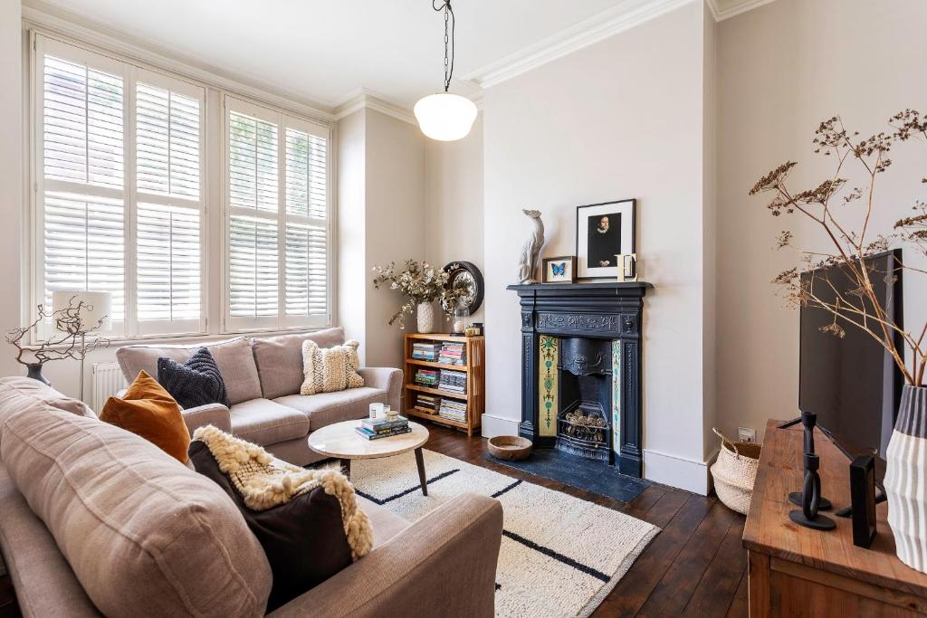 uma sala de estar com um sofá e uma lareira em Tooting's Charming Victorian Garden Hideaway em Londres