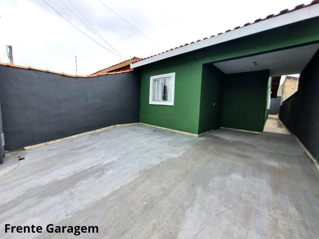a garage with a green wall and a parking lot at CASA DE VERANEIO PERUIBE in Peruíbe
