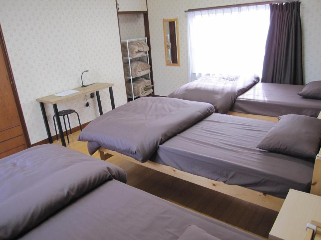 a room with three beds and a table and a window at GuestHouse AZMO - Vacation STAY 35375v in Matsue