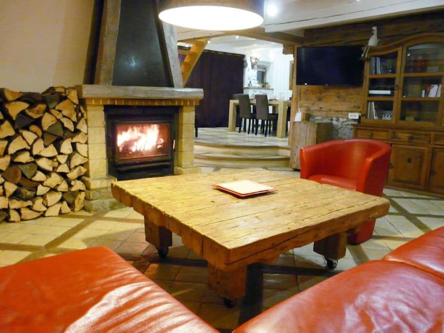 uma sala de estar com uma mesa de madeira e uma lareira em le marmoton em Thônes