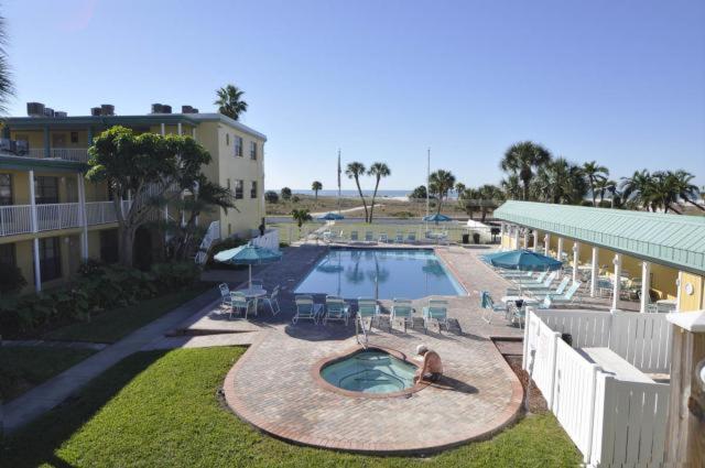 a large swimming pool with chairs and a building at Treasure Island Beach Club 727-360-7096 in St Pete Beach