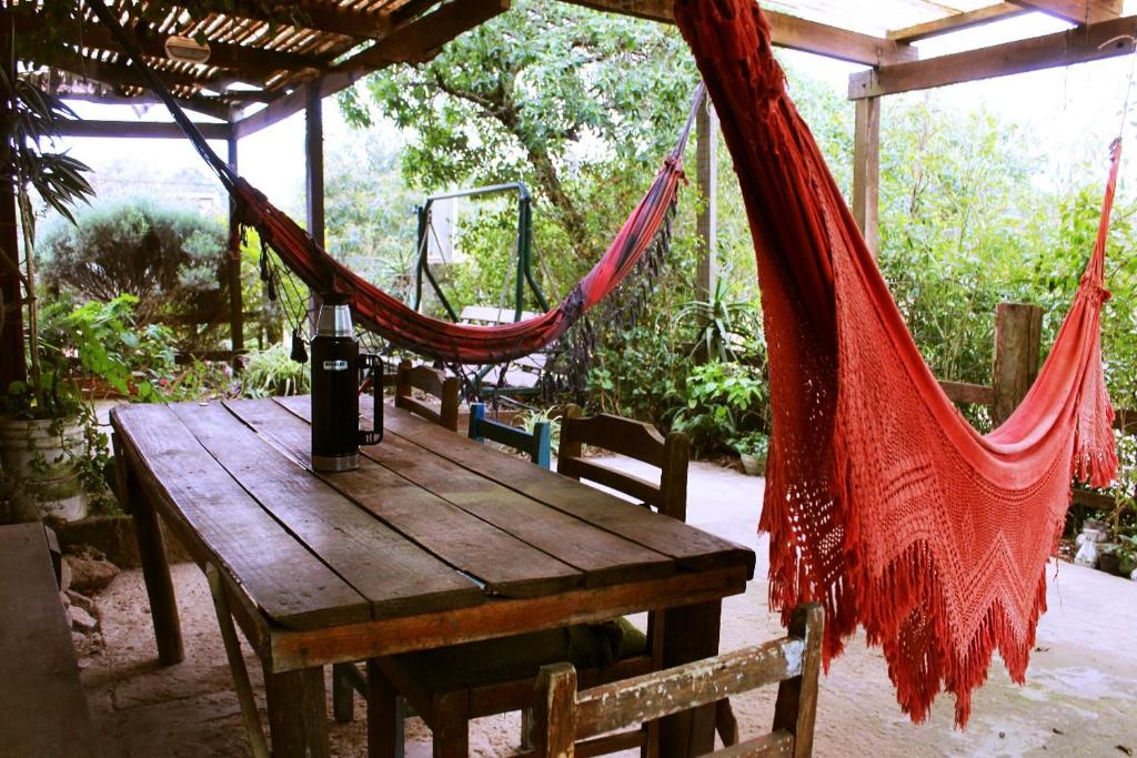 eine Hängematte, die über einem Holztisch in einem Zelt hängt in der Unterkunft Arcadio Hostel Punta del Diablo in Punta Del Diablo