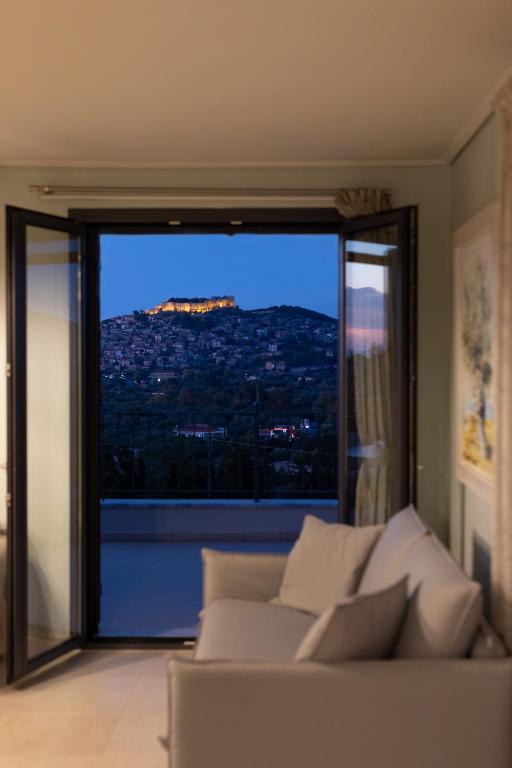 a living room with a couch in front of a large window at Lampetos Houses Molyvos in Mythimna